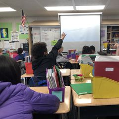 students raising their hands in class