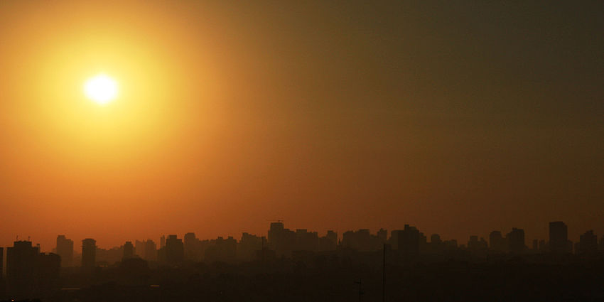 sun over city with brown hazy sky