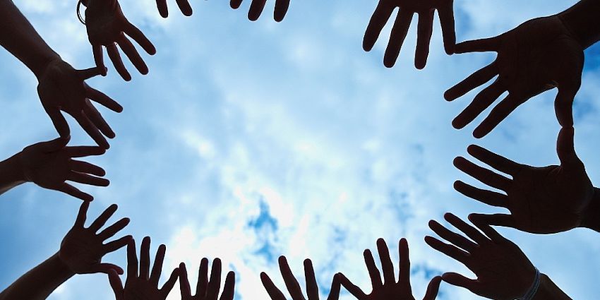 Group of hands with the sky as the background.
