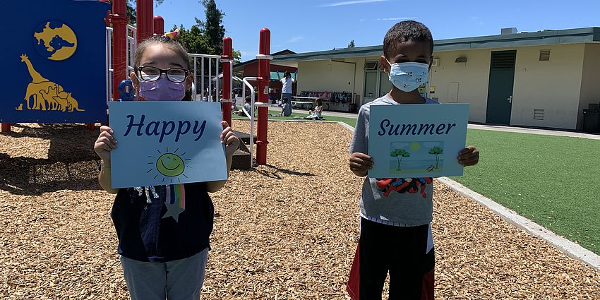 Two students holding "Happy Summer" Signs