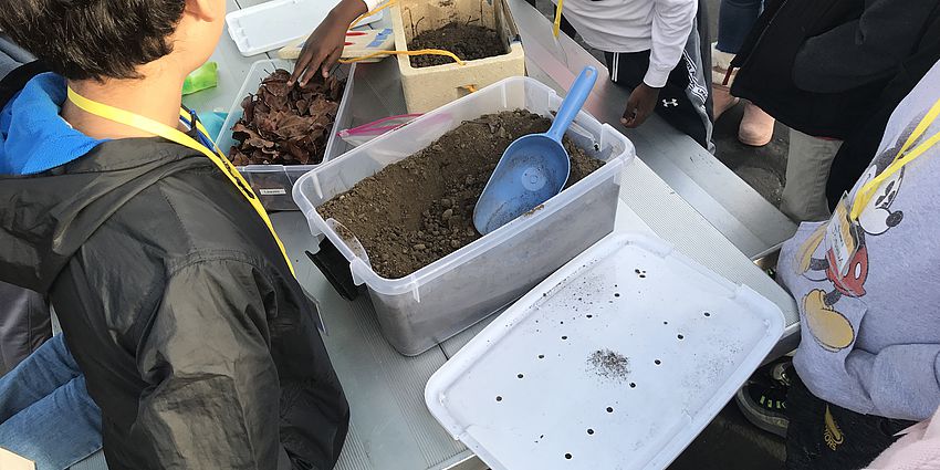 Students around a table with dirt bins