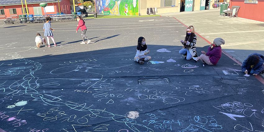 Kindergarten outside using chalk