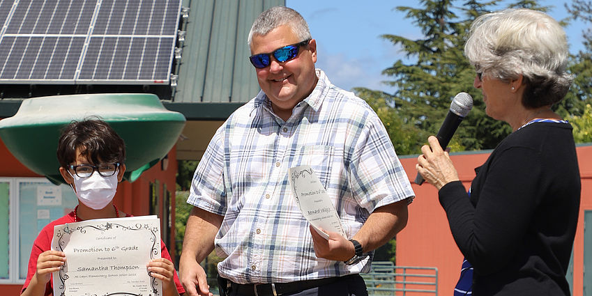 Mr. Brown presenting a promotion certificate to a student