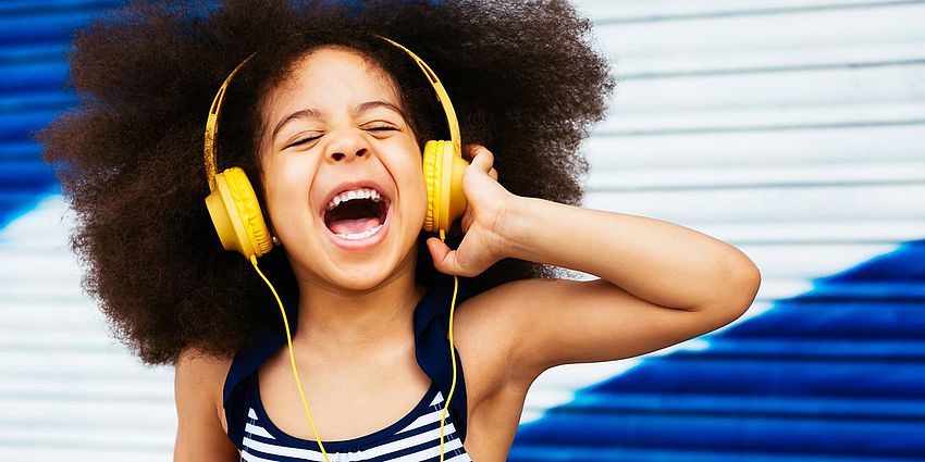 Girl smiling with headphones on her head.