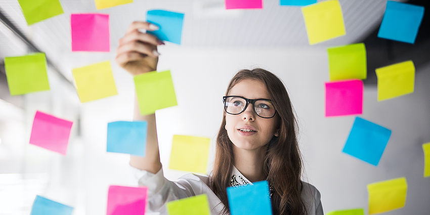 student choosing from a wall of post-it notes