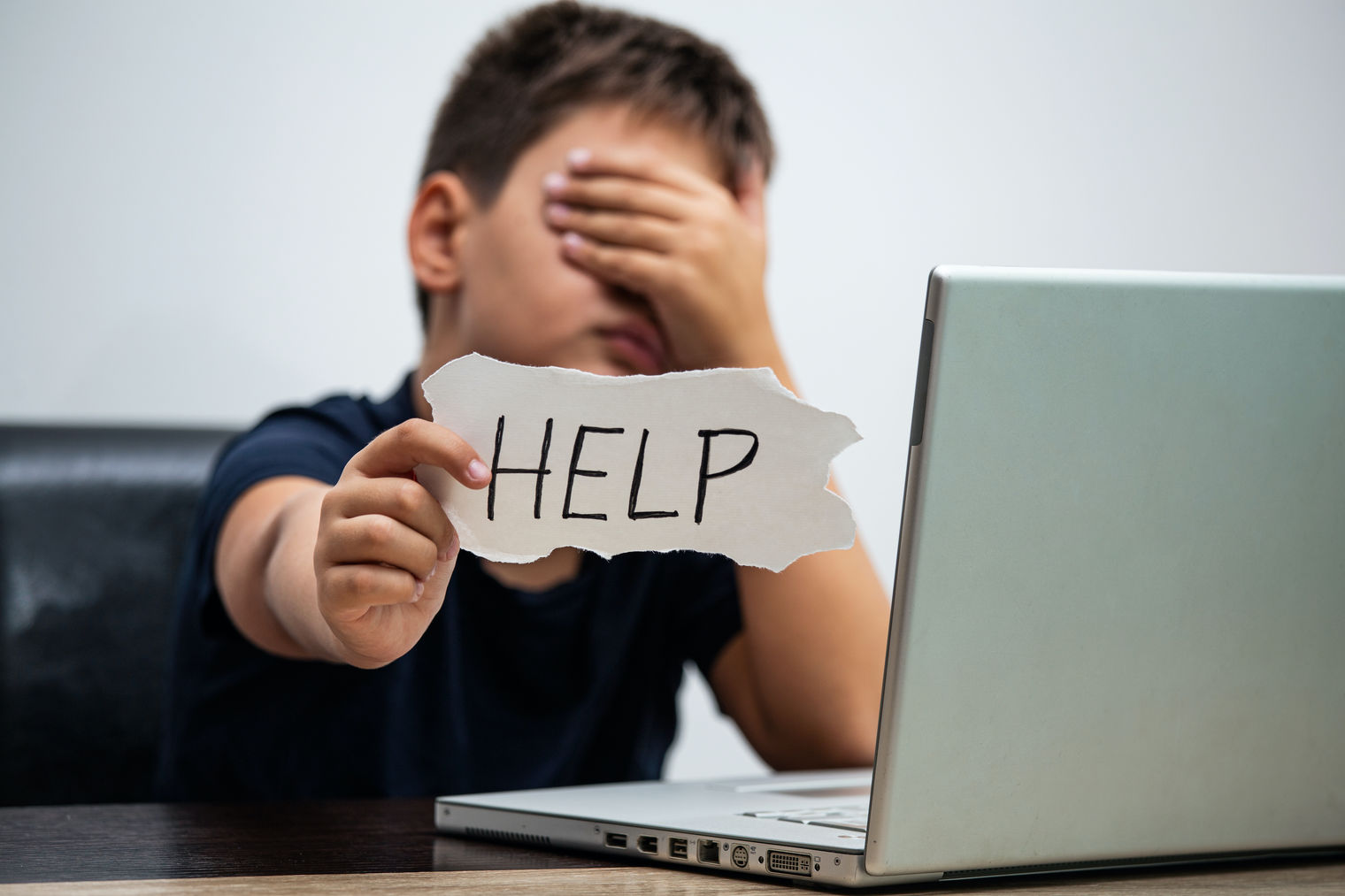 Student at a computer holding up a help sign
