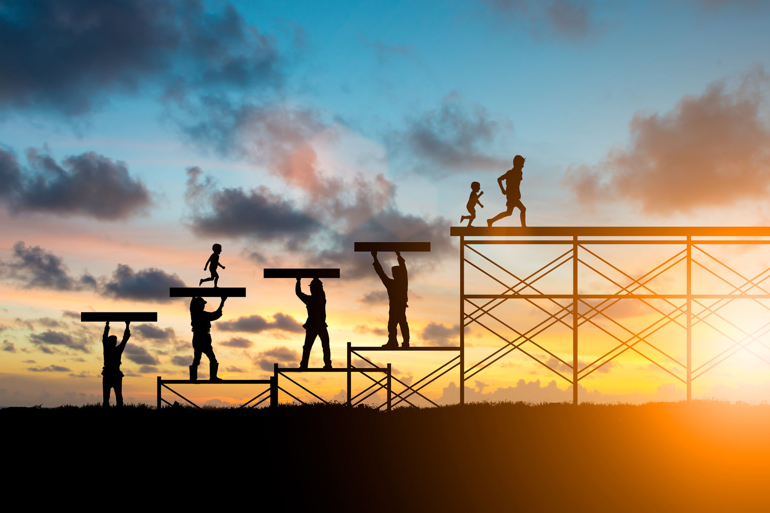 Adults helping children reach the top of a structure