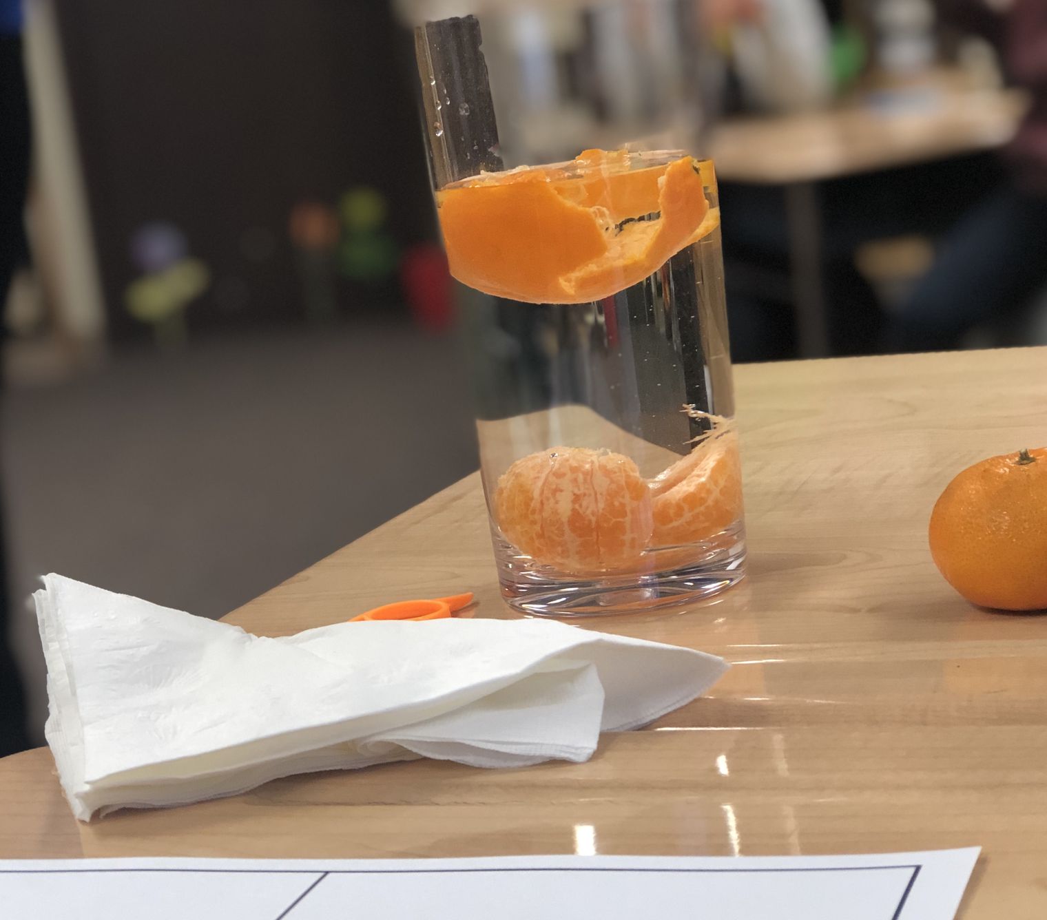 An orange and orange peel in a glass of water