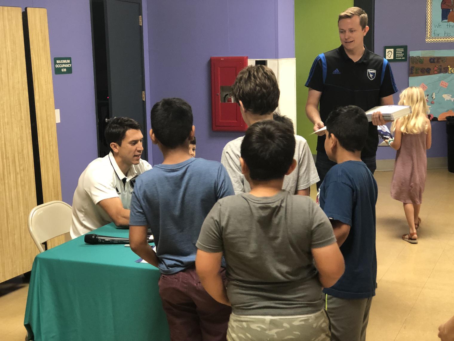 Man signing autographs for children